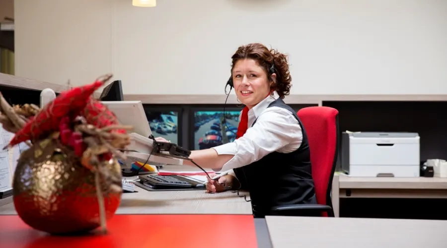 Vrouw zit achter de receptie en kijkt naar de camera
