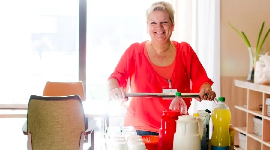 vrouw met cateringkar kijkt lachend in de camera