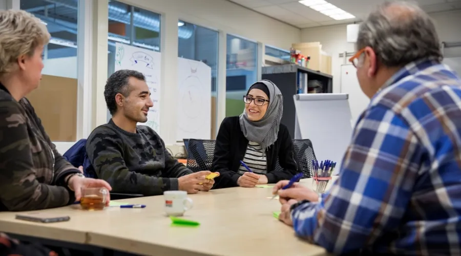 Vergunninghouders die samen aan een tafel zitten en in gesprek zijn met elkaar