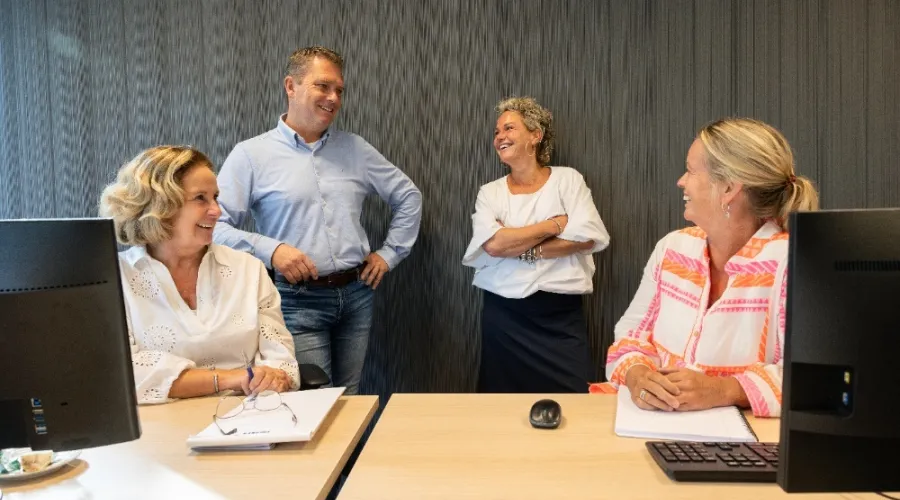 vier collega's van kantoor kijken lachend naar elkaar