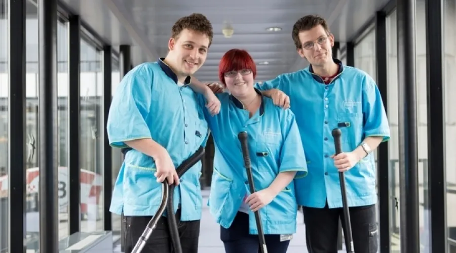 Drie collega's van de schoonmaak staan amicaal met elkaar op de foto