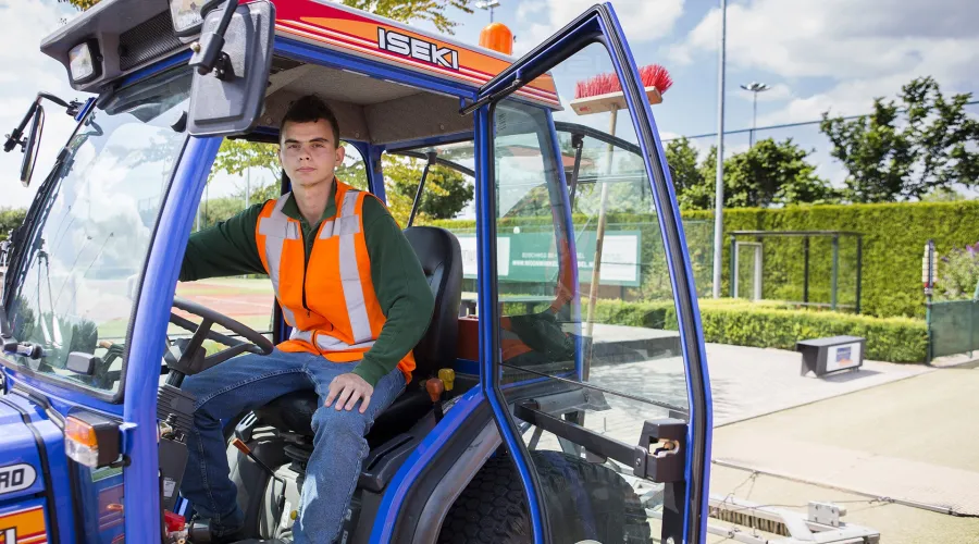 Jonge man op heftruck bij sportterrein