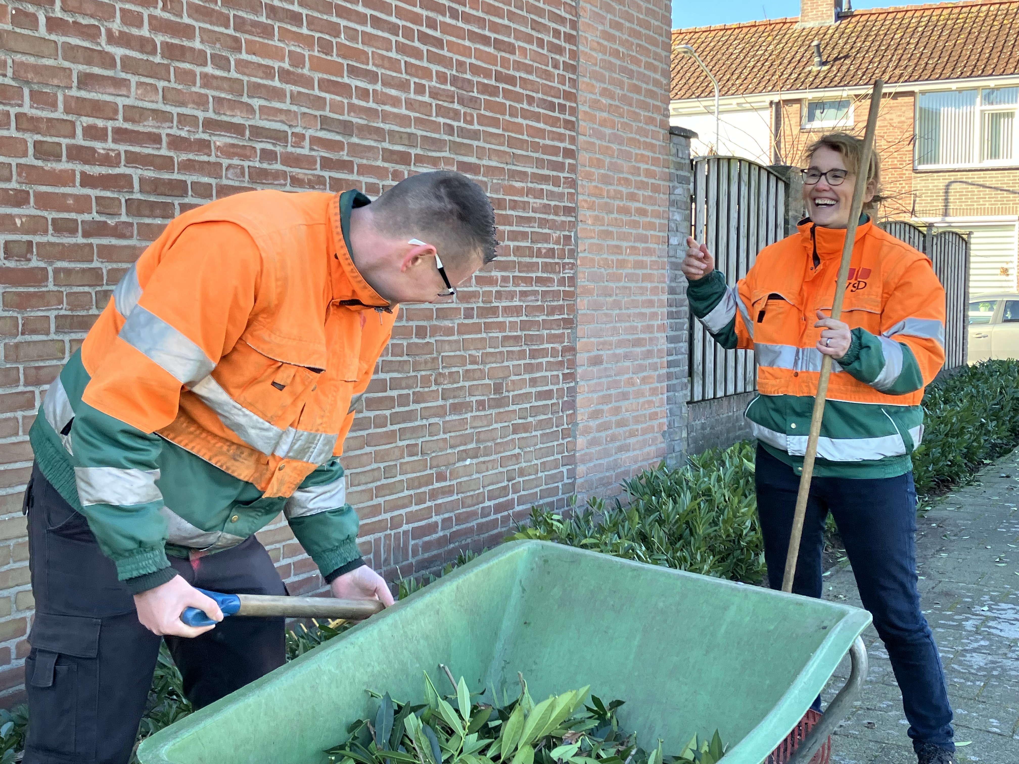 Natasja en medewerker vullen een kruiwagen met groen