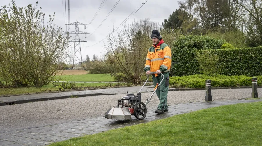 Man loopt met machine om onkruid te verwijderen op de stoep