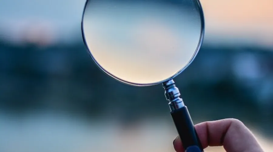 vrouwelijke hand houdt een vergrootglas vast tegen een vage achtergrond